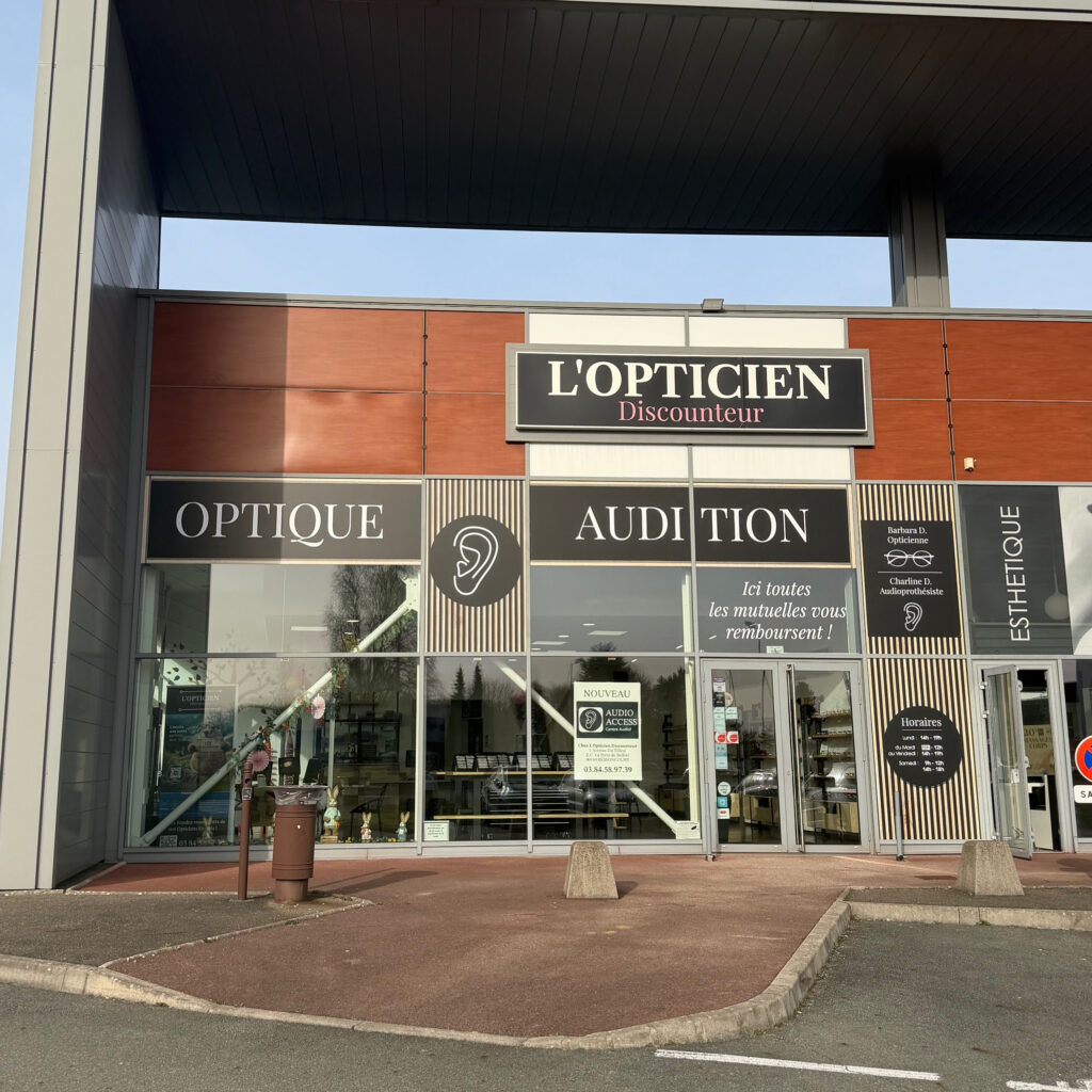 Facade du magasin l'Opticien Discounteur, sur laquelle on voit également l'enseigne Audition. On devine la présence du centre de coiffure passage bleu à côté